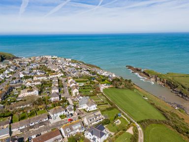 An aerial view of a coastal village with houses roads and green fields by the sea at Tamarama House in Port Isaac
