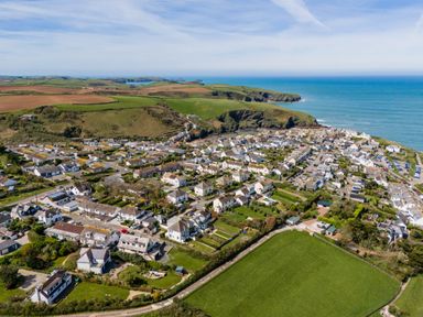 An aerial view of a coastal town with houses green fields and cliffs by the sea at Tamarama House in Port Isaac