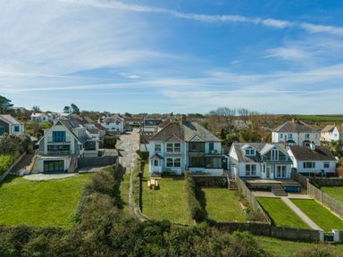 A row of houses with lawns and a clear sky at Tamarama House in Port Isaac