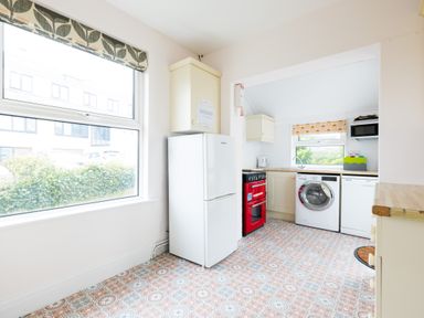 A kitchen with a refrigerator stove washing machine dishwasher and window at Tamarama House in Port Isaac