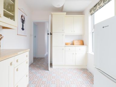 A kitchen with cream cabinets patterned floor and a refrigerator at Tamarama House in Port Isaac
