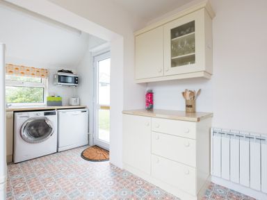 A kitchen with a washing machine dishwasher cabinets microwave and utensils at Tamarama House in Port Isaac