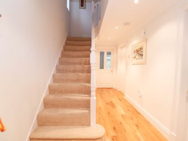 A staircase with beige carpet and a hallway with wooden floor and white walls at 9 Church Farm Rise Aldeburgh