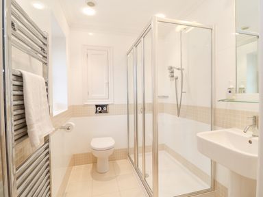 A bathroom with a shower enclosure a toilet a sink and a towel rail at 9 Church Farm Rise Aldeburgh