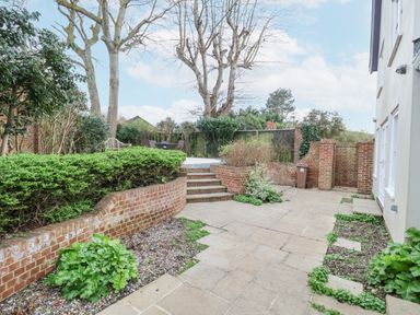 A garden patio area with brick walls and steps leading to a seating area at 9 Church Farm Rise in Aldeburgh