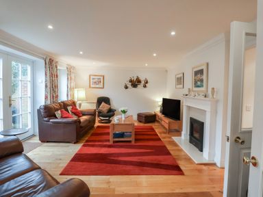 A living room with a sofa, table, and television at 9 Church Farm Rise, Aldeburgh