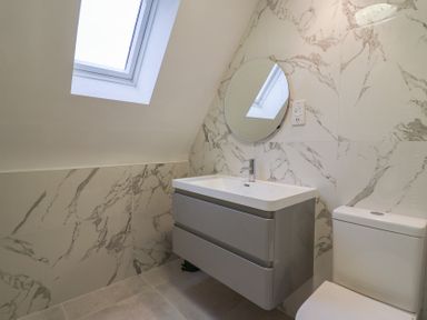 A bathroom with a sink, mirror, and toilet at 9 Church Farm Rise in Aldeburgh