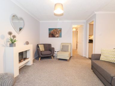 A living room with armchairs a sofa a heart shaped mirror and a painting of a cow at Hill Lodge in Applethwaite 2 Limefitt Park near Windermere