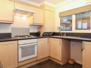A kitchen with gas stove oven wooden cabinets and a window with a view at Hill Lodge in Applethwaite 2 Limefitt Park near Windermere