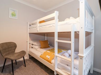 A bedroom with a white bunk bed and a gray chair at Hill Lodge in Applethwaite 2 Limefitt Park near Windermere