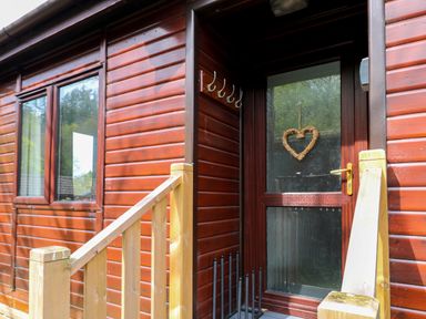 Entrance door with a heart-shaped decoration on the glass of a wooden cabin with railing at Hill Lodge Applethwaite 2 Limefitt Park near Windermere
