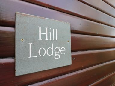 A sign reading Hill Lodge mounted on a wooden exterior wall at Hill Lodge Applethwaite 2 Limefitt Park near Windermere