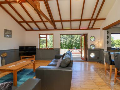 A living room with a black leather sofa a wooden coffee table and a television at Bay Tree Lodge 35 Watermouth near Berrynarbor