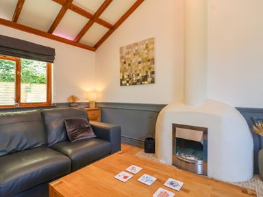 A living room with a black leather sofa a wooden coffee table and a white fireplace at Bay Tree Lodge 35 Watermouth near Berrynarbor