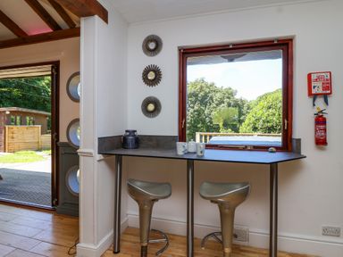 A corner bar table with two stools next to a window with trees outside at Bay Tree Lodge 35 Watermouth near Berrynarbor