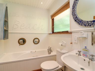 A bathroom with a bathtub toilet sink a window and round mirrors at Bay Tree Lodge 35 Watermouth near Berrynarbor