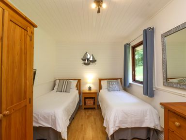 A bedroom with two single beds a wooden wardrobe and mirror at Bay Tree Lodge 35 Watermouth near Berrynarbor