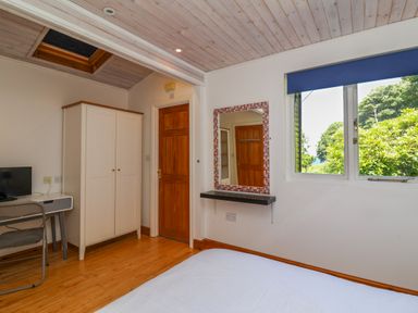 A bedroom with a bed a white wardrobe a wall mirror a desk and a window with a blue blind at Bay Tree Lodge 35 Watermouth near Berrynarbor
