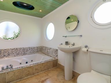 A bathroom with a bathtub a pedestal sink a toilet and round windows at Bay Tree Lodge 35 Watermouth near Berrynarbor