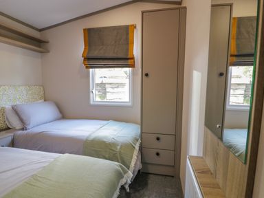 A bedroom with two single beds a window with a blind a wardrobe and a mirror at 11A Mansion View in Cove near Kilcreggan
