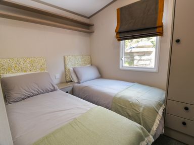 A bedroom with two single beds a window and a wardrobe at 11A Mansion View in Cove near Kilcreggan