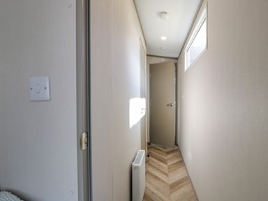 A narrow hallway with wood patterned floor a radiator and a partially open door at 11A Mansion View in Cove near Kilcreggan