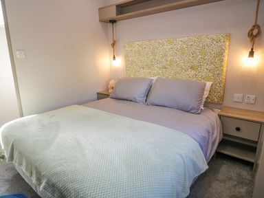 A bedroom with a double bed two bedside tables and hanging light bulbs at 11A Mansion View in Cove near Kilcreggan