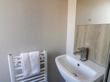 A bathroom sink with a faucet and a towel rack with two white towels at 11A Mansion View in Cove near Kilcreggan