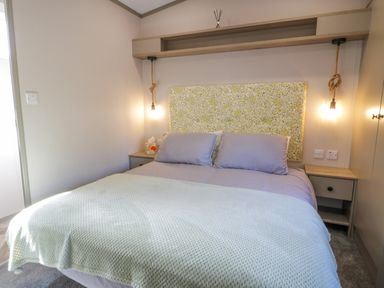 A bedroom with a bed two pillows bedside tables and hanging lights at 11A Mansion View in Cove near Kilcreggan