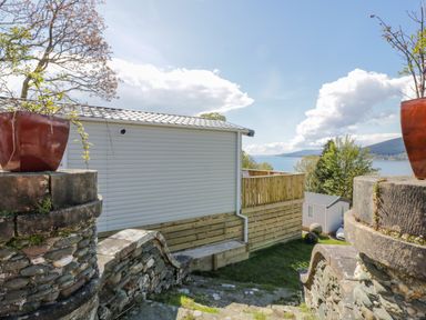 Stone steps with planters on stone walls leading down to mobile homes near a body of water at 11A Mansion View in Cove near Kilcreggan