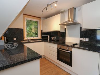 A kitchen with black speckled countertops white cabinets a window microwave toaster and oven at 27 Invergarry Lodges South Laggan near Invergarry