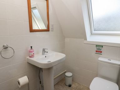 A bathroom with a pedestal sink a mirror above it a toilet and a frosted window at 27 Invergarry Lodges South Laggan near Invergarry