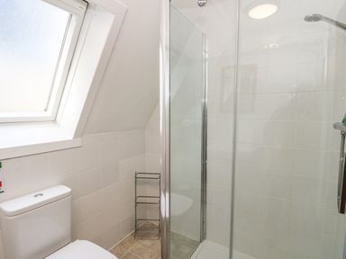 A bathroom with a toilet a corner shower with glass doors a metal rack and a frosted window at 27 Invergarry Lodges in South Laggan near Invergarry