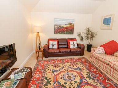 A living room with two sofas a colorful rug a floor lamp paintings and a plant at Wellington Lodge Cottage Middleton Tyas