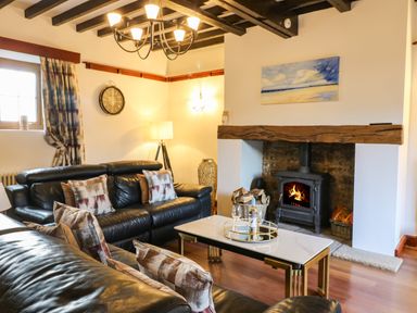 A living room with leather sofas a coffee table a wood burning stove and a clock on the wall at Winding Wheel Cottage Cambois near Ashington