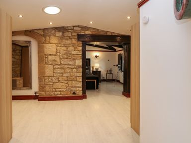 A room with a stone wall and doorway leading to a bedroom with a telescope at Winding Wheel Cottage in Cambois near Ashington