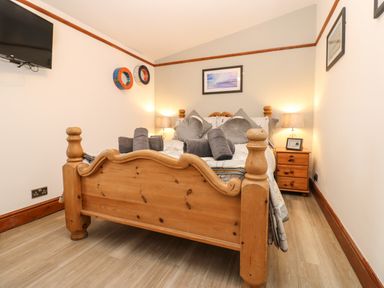 A bedroom with a wooden bed and nightstands with lamps at Winding Wheel Cottage in Cambois near Ashington