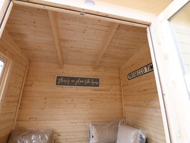 A wooden room with cushions and signs saying theres no place like home and prosecco time at Winding Wheel Cottage in Cambois near Ashington