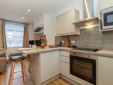 A kitchen with a built in oven stove a countertop with plates glasses and a vase of flowers at Jacks Cottage in Keswick