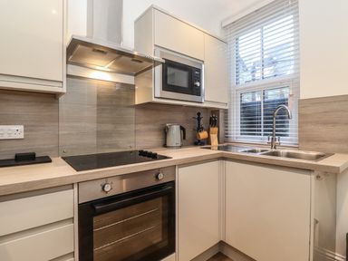 A kitchen with a stovetop oven microwave kettle knife block sink and window at Jacks Cottage in Keswick