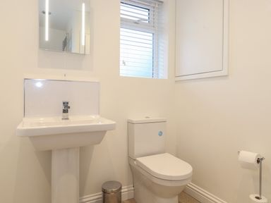 A bathroom with a pedestal sink toilet small trash bin and window with blinds at Jacks Cottage in Keswick