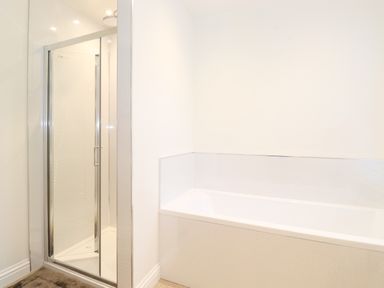 A bathroom with a shower enclosure and a bathtub at Jacks Cottage in Keswick