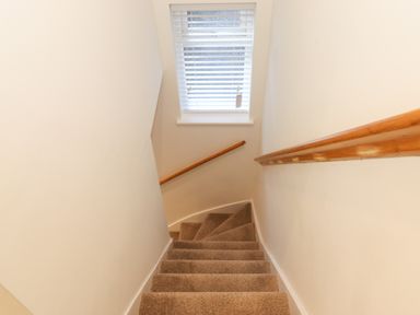 A staircase with carpeted steps and wooden handrails with a window at the top at Jack's Cottage in Keswick