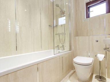 A bathroom with a bathtub and shower next to a toilet and a window at 19 Burgh Island Causeway in Bigbury-On-Sea