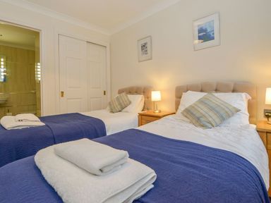 A bedroom with two single beds with blue blankets and folded towels at 19 Burgh Island Causeway in Bigbury-On-Sea