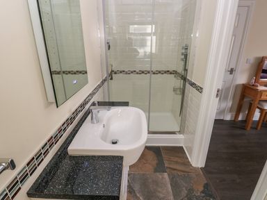 A bathroom with a sink and a glass shower enclosure at Llygad Y Lleuad Moon in Burry Port
