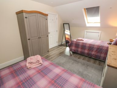 A bedroom with two single beds a wardrobe a standing mirror and a skylight window at Llygad Y Lleuad Moon in Burry Port