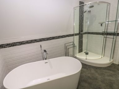 A bathroom with a freestanding bathtub and a glass-enclosed corner shower at Llygad Yr Haul Sun in Burry Port