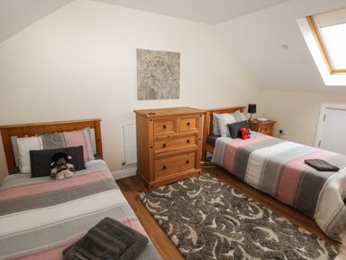 A bedroom with two single beds wooden furniture and a window in the ceiling at Llygad Yr Haul in Burry Port