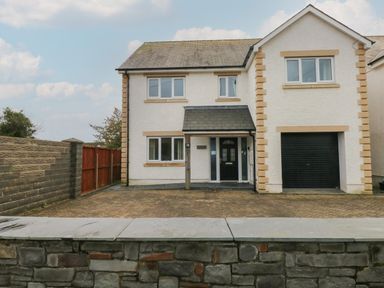 A detached house with a driveway garage and paved front yard at Llygad Yr Haul (Sun) in Burry Port